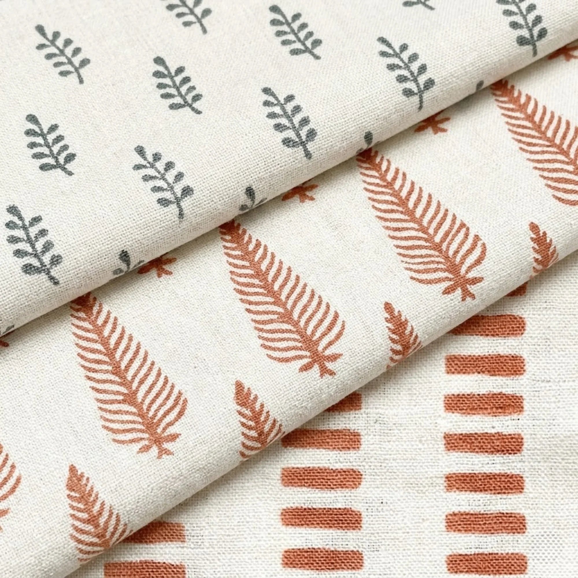 A curated stack of folded pre-cut fabric remnants, featuring hand-block printed linen and cotton textiles in various botanical patterns for the Thread to Form sustainable archive.