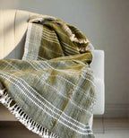 Textured green blanket with white patterns draped over a white chair.