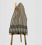 Black and white striped towel draped over a wooden chair on a light gray background