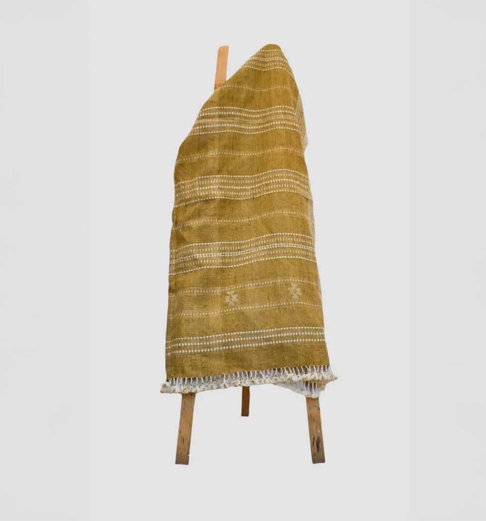 Yellow patterned dress on a wooden stool against a white background