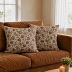 Hand block printed natural linen pillow covers featuring red and plum botanical floral vine patterns on a sofa.