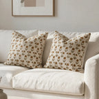 Two linen pillow covers with mustard and olive floral block-printed motifs on a natural ground, resting on a white sofa.