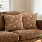Mustard linen pillow covers featuring hand-blocked pink beige floral vine patterns on a brown sofa.