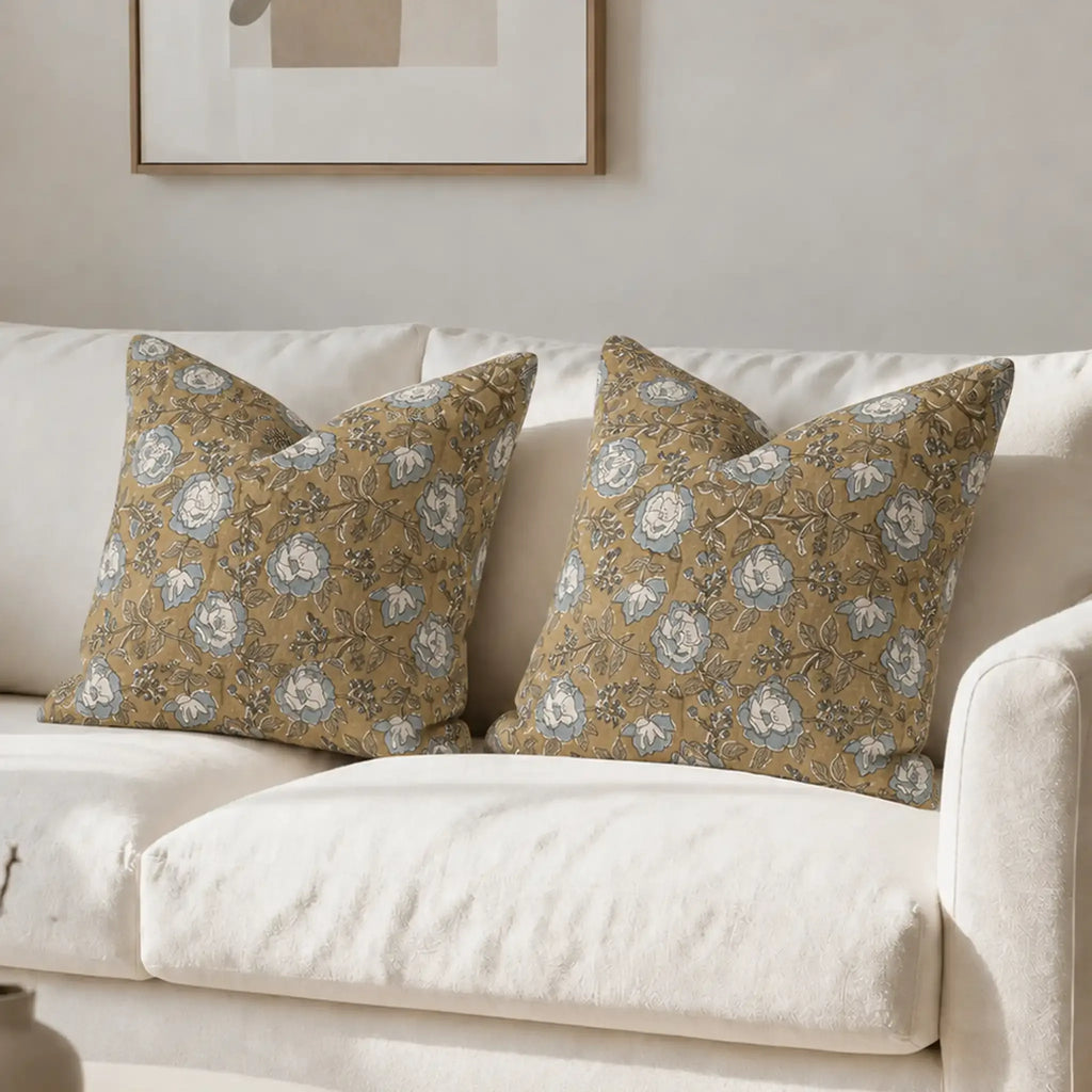 Hand block-printed linen pillow covers featuring botanical floral vines in beige, ice blue, and brown on a white sofa.