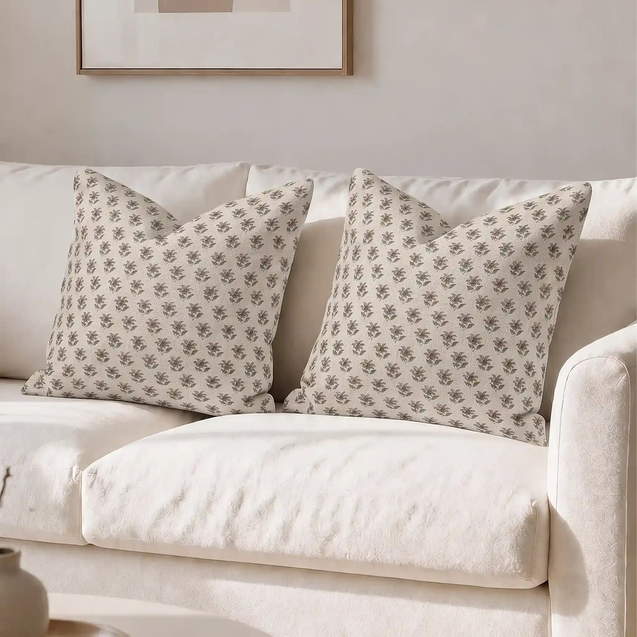 Hand block printed linen pillow covers in natural, ice blue, and plum wine ditsy floral buti pattern on a white sofa.