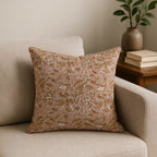 Hand block printed linen pillow cover in dawn pink with beige and plum wine floral vine patterns on a neutral sofa.