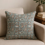 Hand block printed linen pillow cover in ice blue with blush pink floral vines on a neutral sofa.