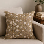 Hand block printed linen pillow cover in beige with pale green floral vines and red outlines on a neutral sofa.