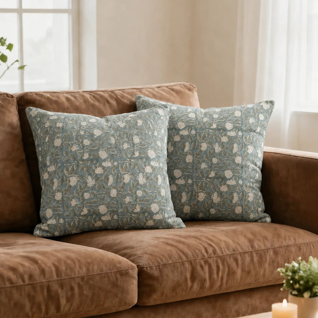 Hand block printed ice blue linen pillow covers featuring pale green botanical floral vines on a brown sofa.