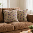 Hand block printed sage green linen pillow covers featuring purple and olive floral vine motifs on a brown sofa.