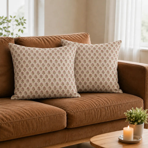 Hand block printed linen pillow covers featuring a natural floral buti pattern in blush pink and plum wine on a sofa.