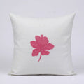 A square off-white linen throw pillow featuring a prominent pink embroidered hibiscus flower in the center, set against a clean light gray background.