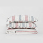 Striped bedding set with ruffled edges on a light gray background