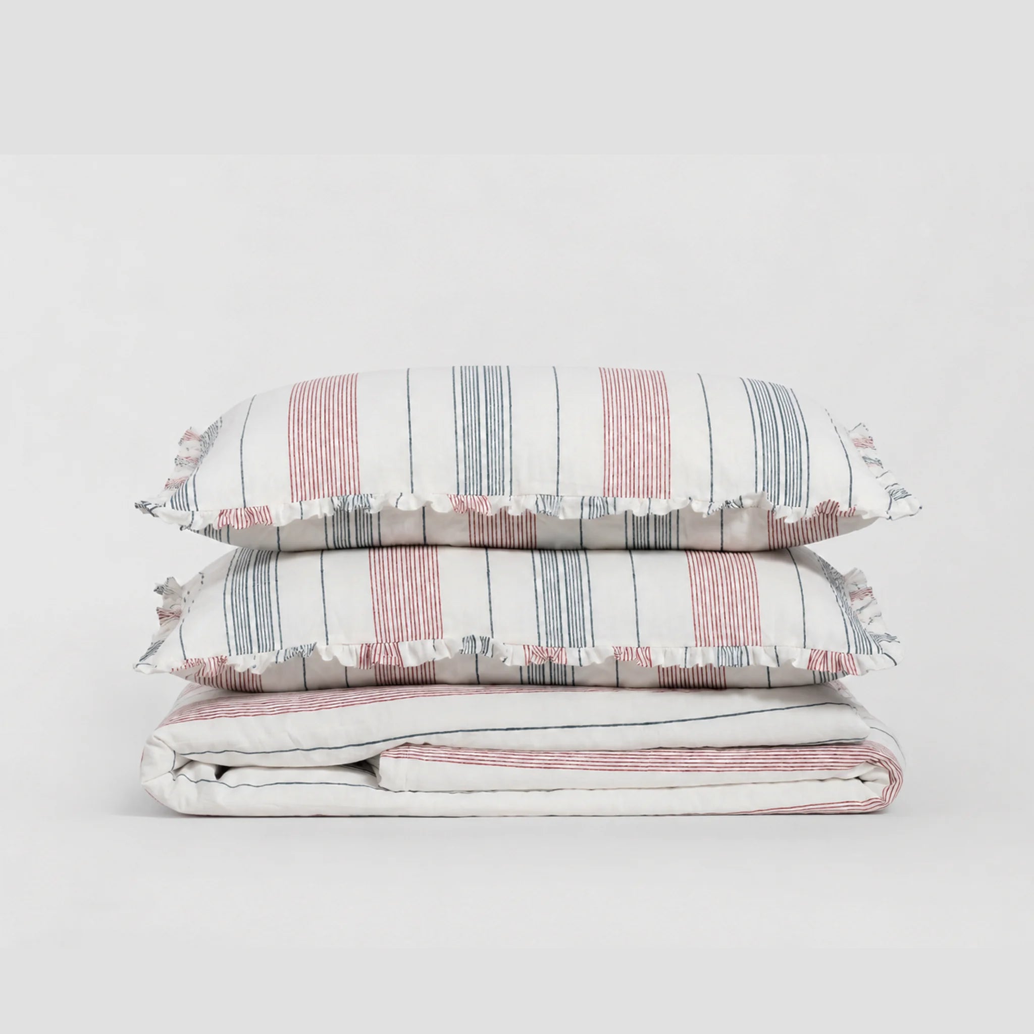 Striped bedding set with ruffled edges on a light gray background
