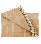 Beige woven blanket with geometric patterns and tassels on a white background
