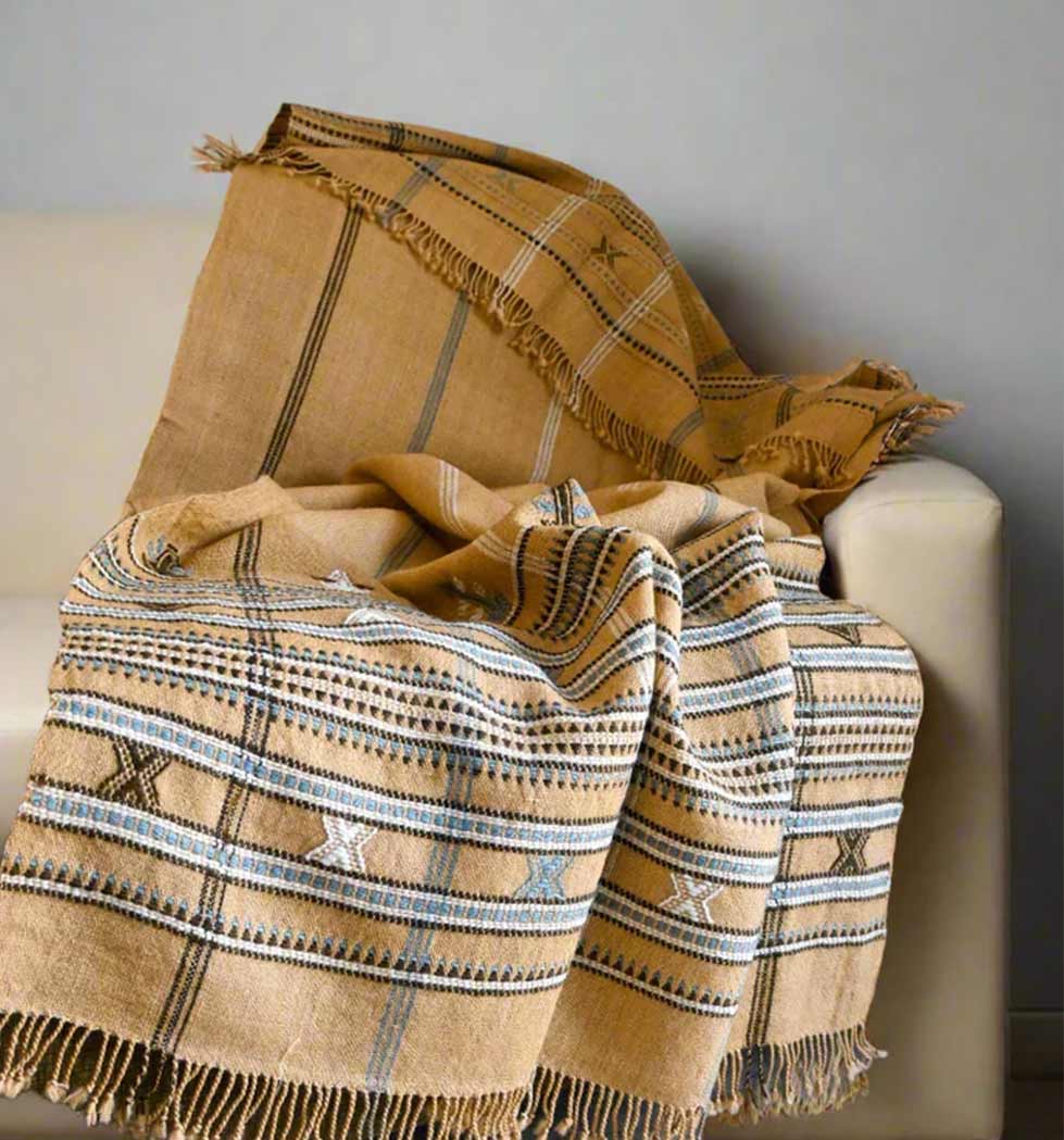 Textured brown blanket with geometric patterns draped over a surface.