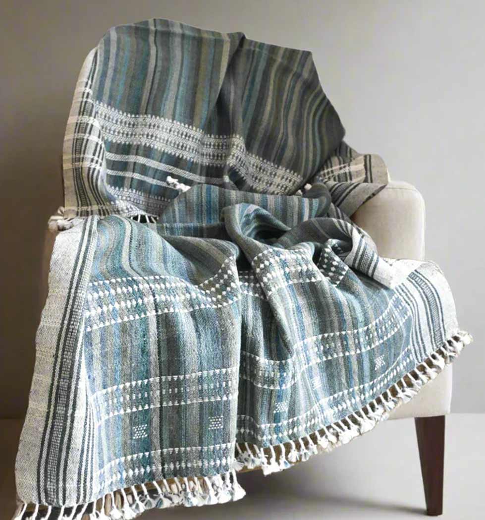 Textured blue and gray plaid blanket draped over a chair against a neutral background