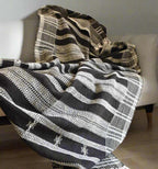 Textured blanket with black, white, and beige pattern draped over a sofa.