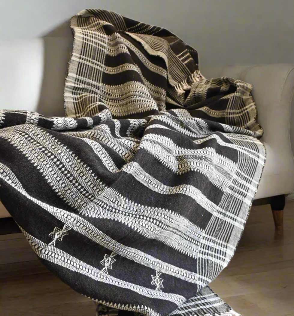 Textured blanket with black, white, and beige pattern draped over a sofa.