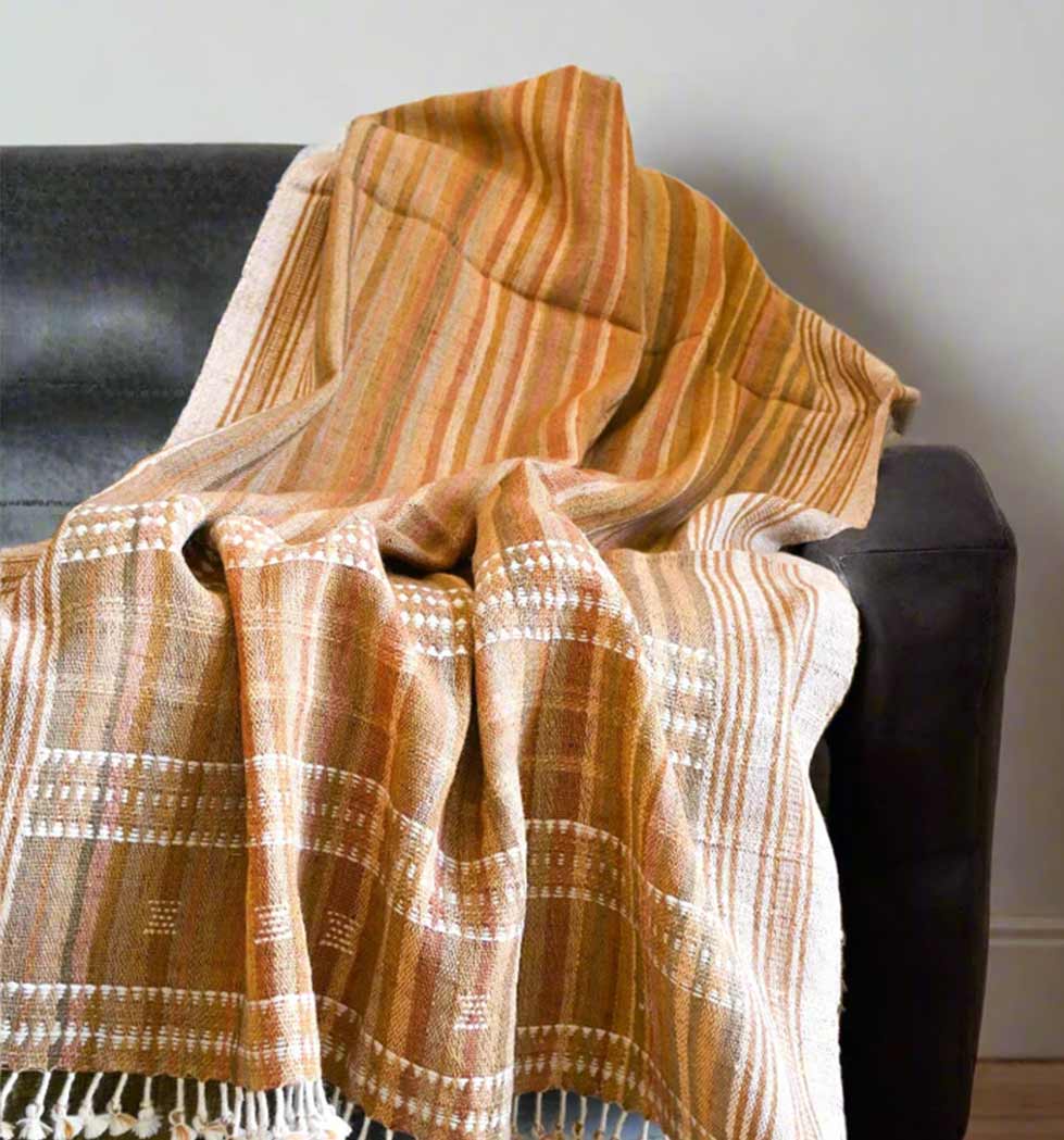 Plaid blanket draped over a black chair against a neutral background