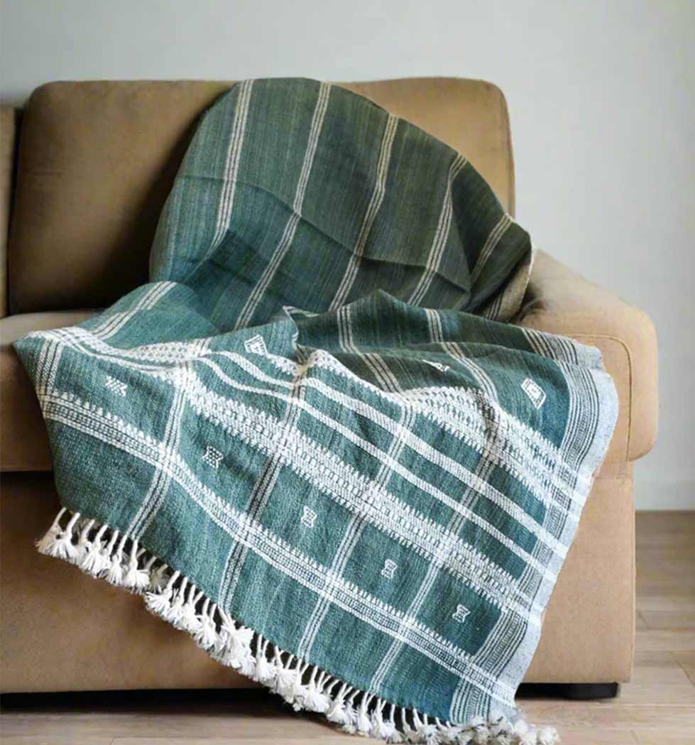 Green plaid blanket with white patterns draped over a brown sofa.