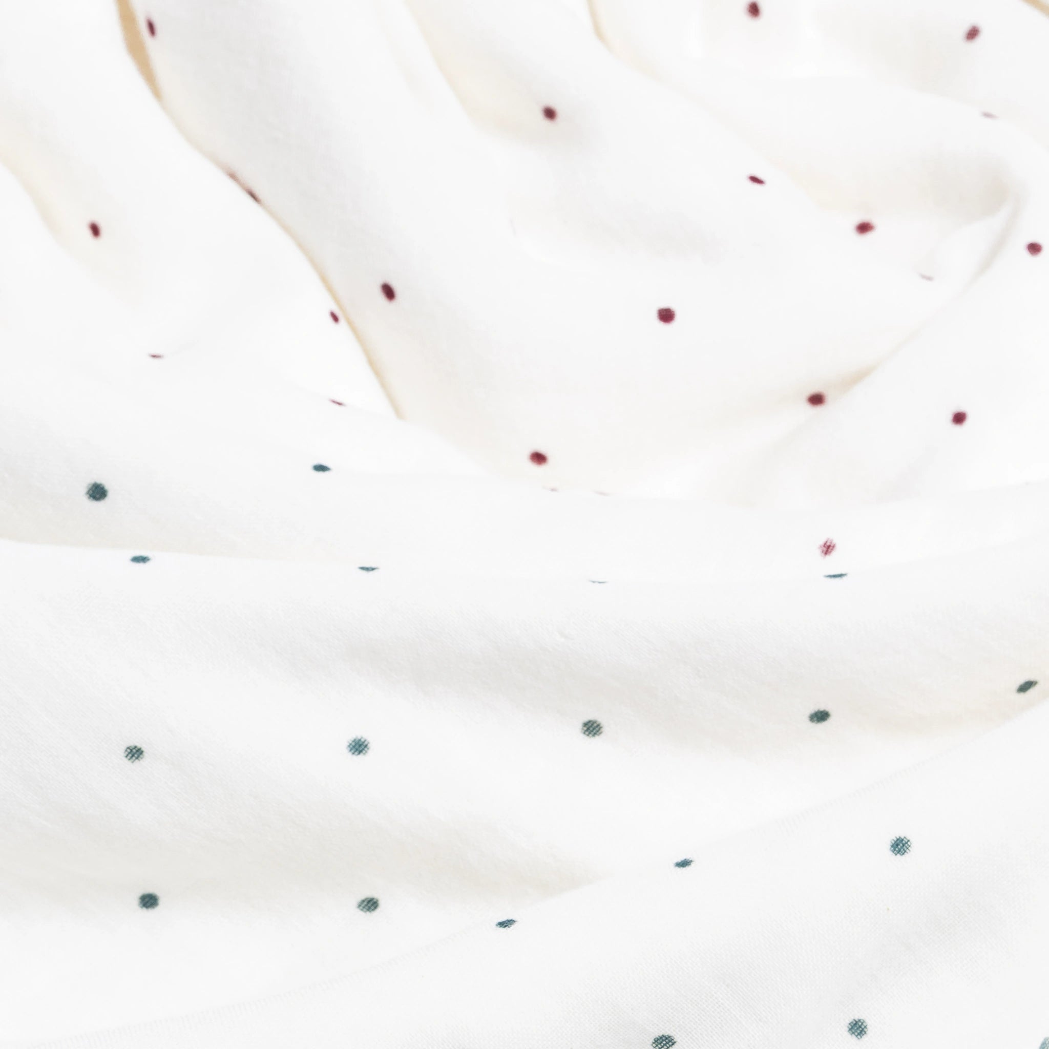 Close-up of a white fabric with small red and green polka dots.