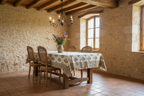 Dining room with rustic stone walls, wooden floor, and a table set with a floral arrangement.