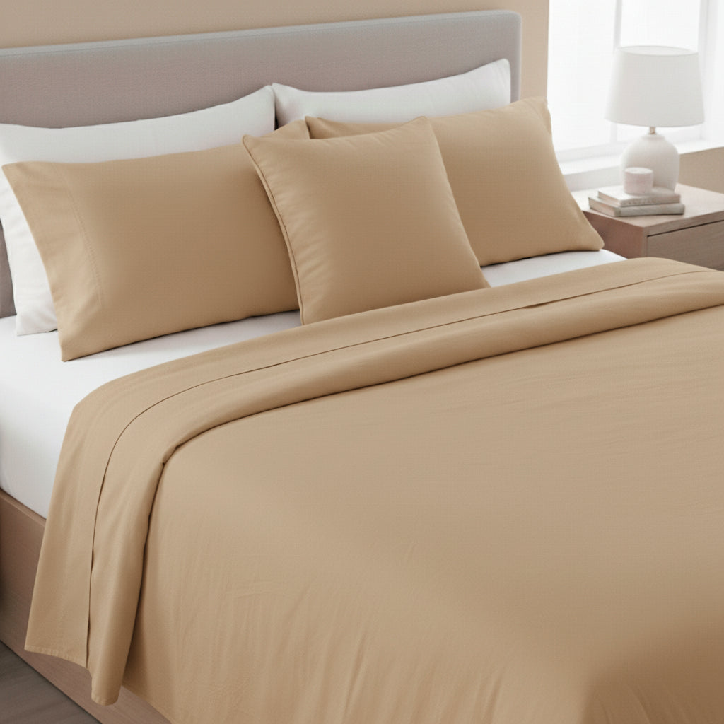 Beige bed sheets and pillows on a bed with a neutral headboard.