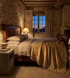 Cozy bedroom with stone walls, wooden bed, and lit fireplace showing a Artisanally embroidered tan dust throw blanket