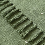 Close-up of a green embroidered blanket with tassels